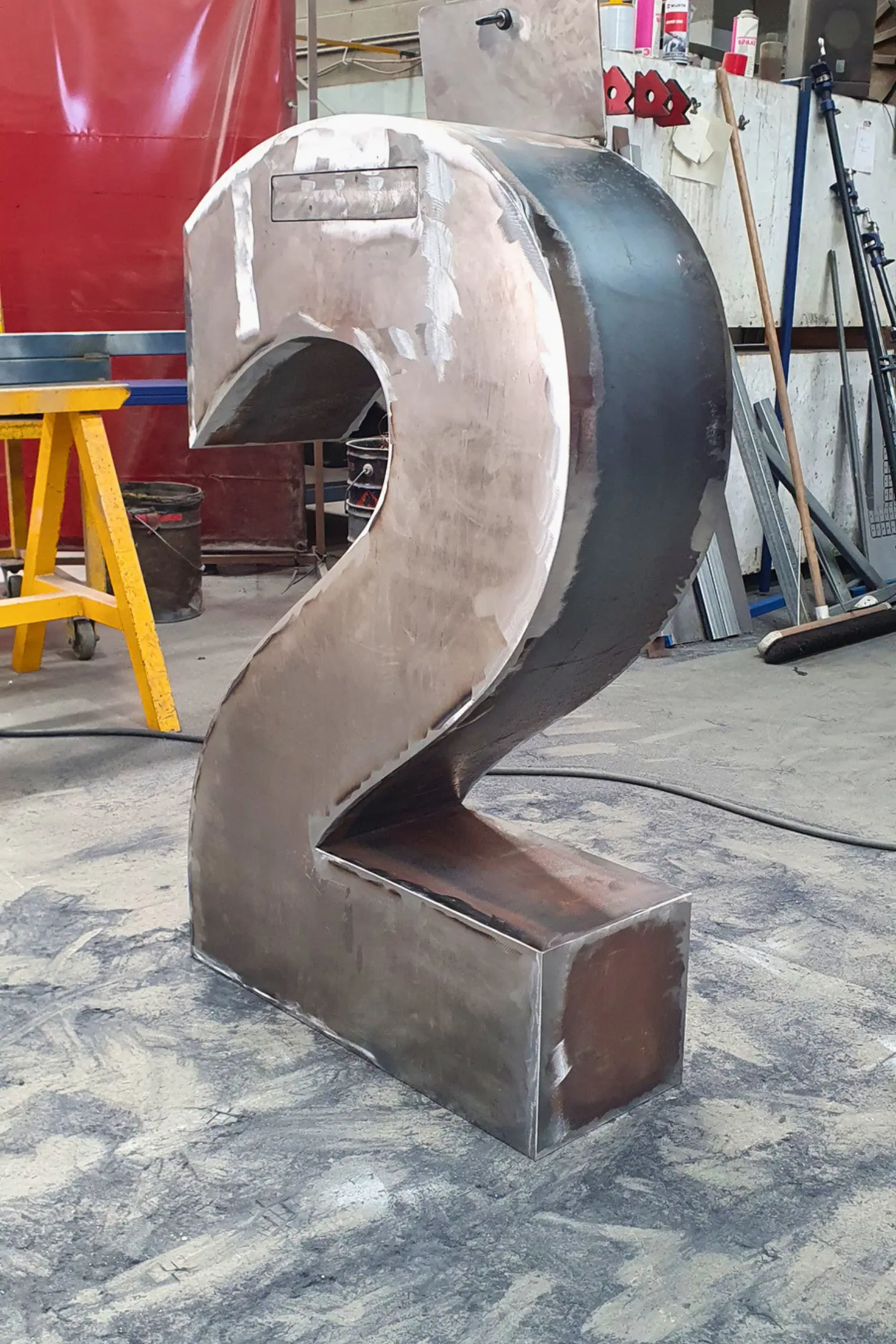 2 number Sculpture during metal polishing process showing grinding and surface finishing stages